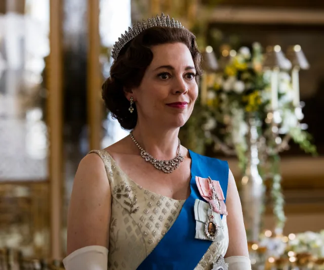 Olivia Colman as Queen Elizabeth II, wearing a tiara and sash in a formal setting from "The Crown."