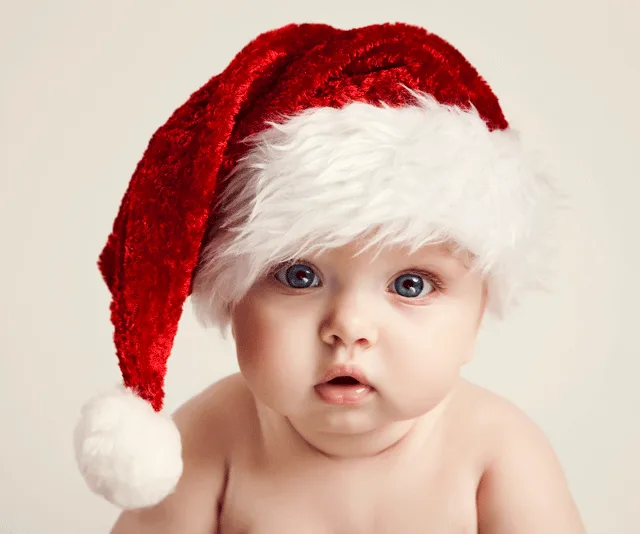 Baby wearing a red and white Santa hat, looking ahead with a curious expression.
