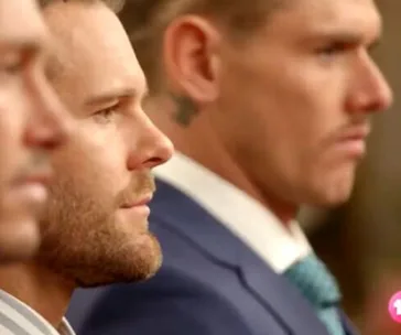 Men in suits focused and serious at a formal gathering, seen in profile.