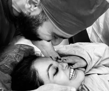 A couple shares a joyful embrace in a hospital setting, celebrating the birth of their child.