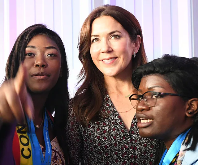 Three women smiling and posing for a photo together indoors.
