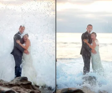 Bride and groom at the beach get splashed by a large wave, laughing and soaked.