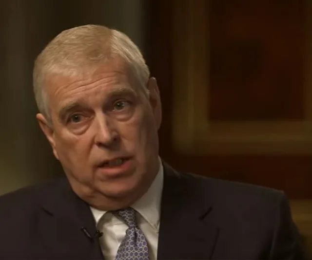 A man in a suit and tie speaking during a formal interview, with a serious expression.