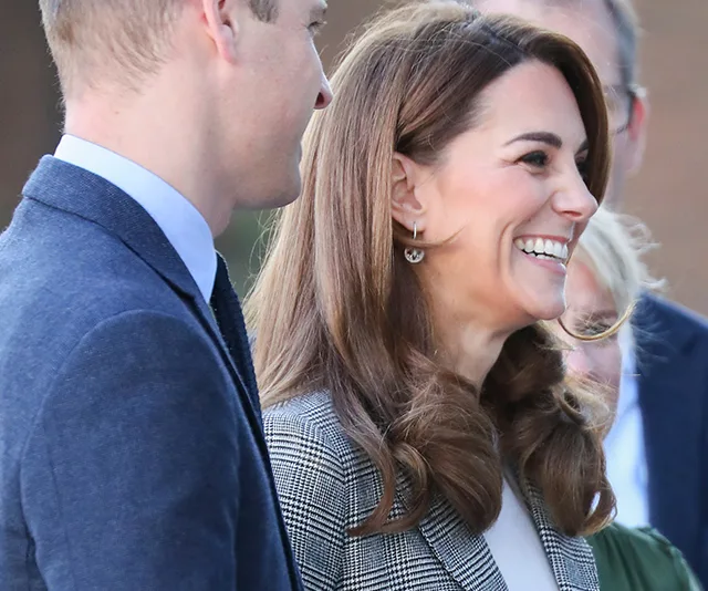 A woman smiling, standing outdoors next to a man in a suit, both partially visible.