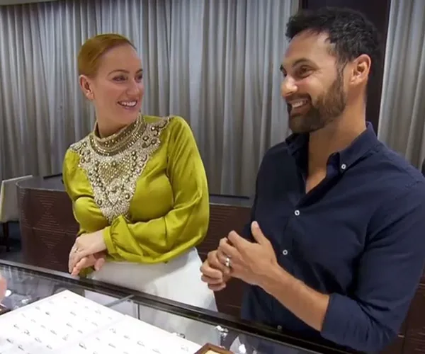 A couple smiling while shopping for jewelry together in a store.