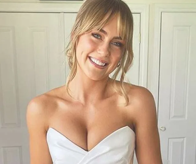 Bride in a white strapless wedding dress, smiling indoors.