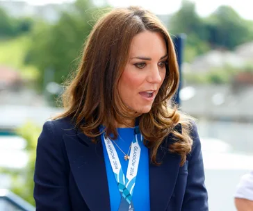 A woman wearing a lanyard with "Glasgow 2014" stands outdoors, with an expression of surprise or interest.