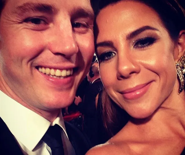 Couple taking a close-up selfie at an event, smiling warmly into the camera.