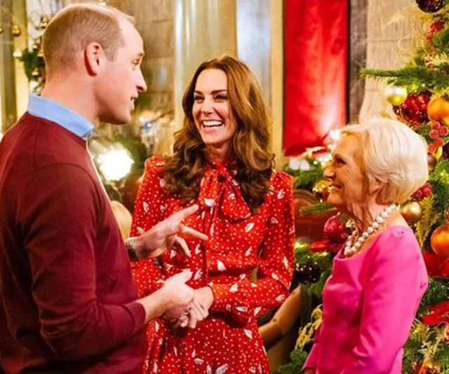 A festive gathering with a decorated Christmas tree in the background, featuring three people smiling and conversing.