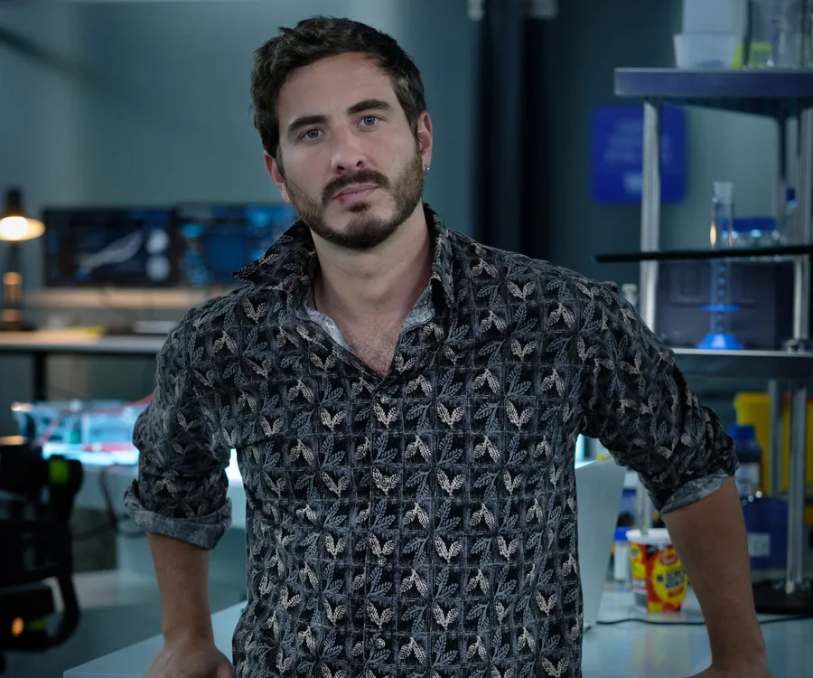 Ryan Corr as a character from "The Commons" stands in a lab with a thoughtful expression.