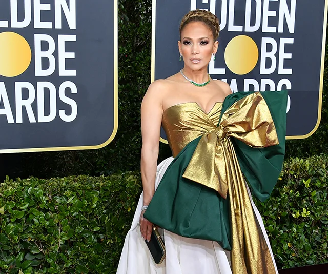 Woman in elaborate gold and green bow dress at Golden Globes event.
