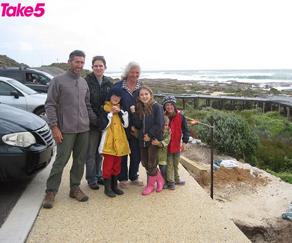 Family posing by the coast with ocean and rugged landscape in the background, labeled "Take 5" in the corner.