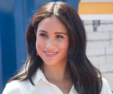 I don't know who this is. A woman with long brown hair smiles in outdoor lighting, wearing a white shirt.