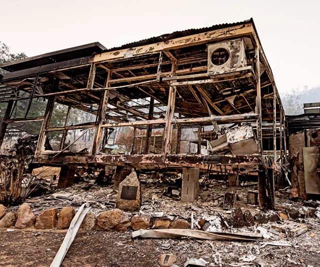 Burnt remains of a house in Glen Innes, Australia, showing charred debris and skeletal framework after bushfires.