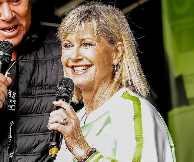 Singer with a microphone smiling at Fire Fight Australia concert.