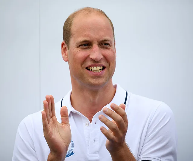 A person in a white polo shirt clapping and smiling against a plain background.