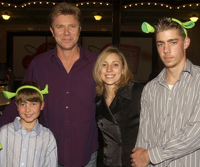 Group of four people, including three wearing Shrek ear headbands, smiling at an event.