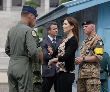 Princess Mary speaking with military personnel at a border area, with two men and a soldier in uniform nearby.
