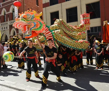 Performers animate a colorful dragon during a Chinese New Year parade on a sunny street in Australia.