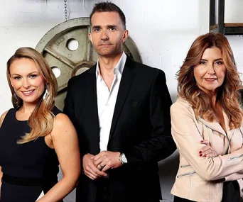 Three people standing in a row, dressed in formal attire, posing in front of industrial decor.