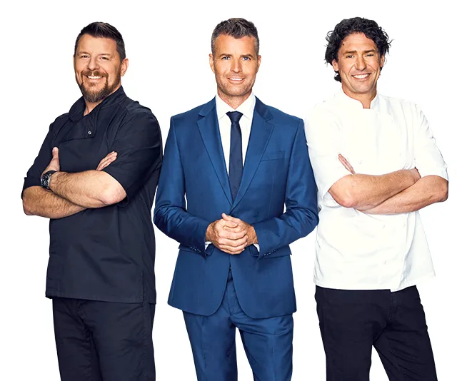 Three men standing, two in chef outfits, one in a blue suit, smiling with arms crossed, against a white background.