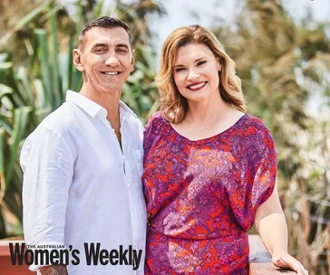 A smiling couple poses outdoors, with greenery in the background, featured in Australian Women’s Weekly magazine.