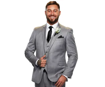 Man in a gray suit with a flower boutonniere, smiling confidently against a white background.