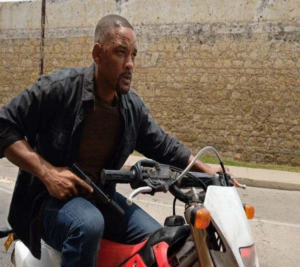 A man riding a motorbike in an action scene, holding a weapon, from the movie "Gemini Man."