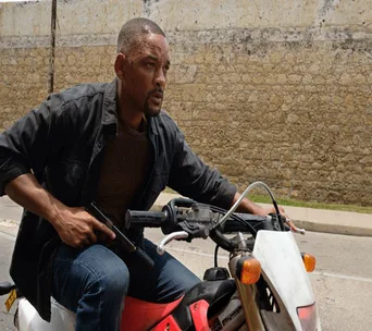 A man riding a motorbike in an action scene, holding a weapon, from the movie "Gemini Man."