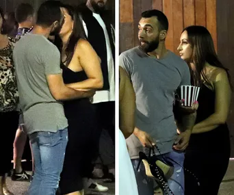 A couple embraces and talks in a lively outdoor setting at night.