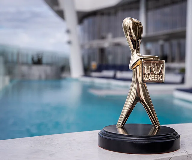 TV Week Logie Award trophy on a stone ledge by a pool with a building in the background.