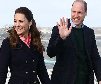 Prince William and Kate Middleton smiling and waving during a public appearance.