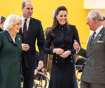 Royal family members, including two women and two men, smiling and conversing indoors.