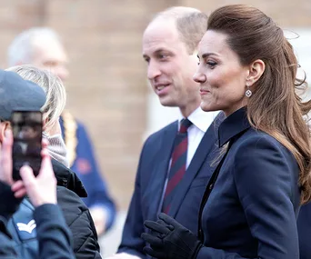 Kate Middleton and Prince William smiling and interacting with people outside during a public event.