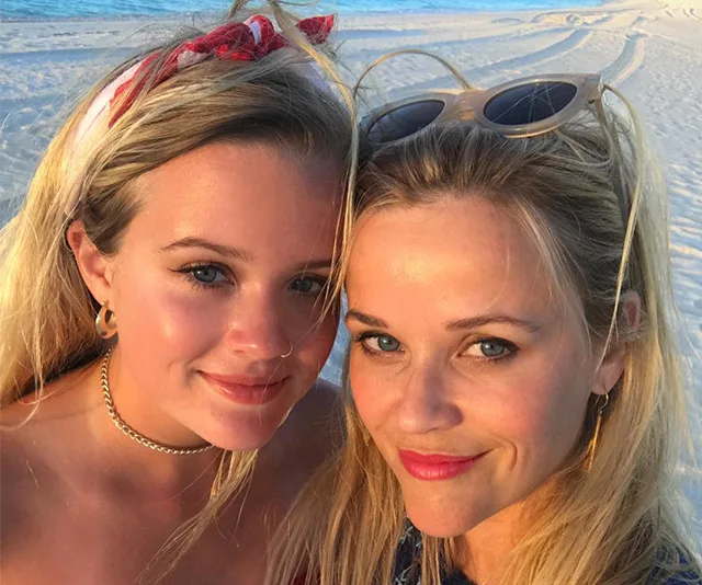 Mother and daughter smiling at the beach during sunset.