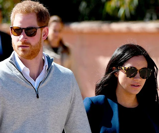 A couple wearing sunglasses and casual clothing walking outdoors on a sunny day.