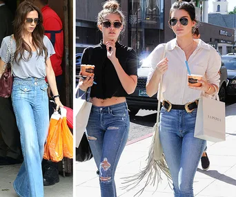 Women in sunglasses wearing denim jeans, holding drinks and shopping bags, walking on a sunny street.