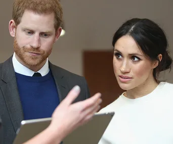 Couple attentively looks at a person's gesture while being shown a tablet.