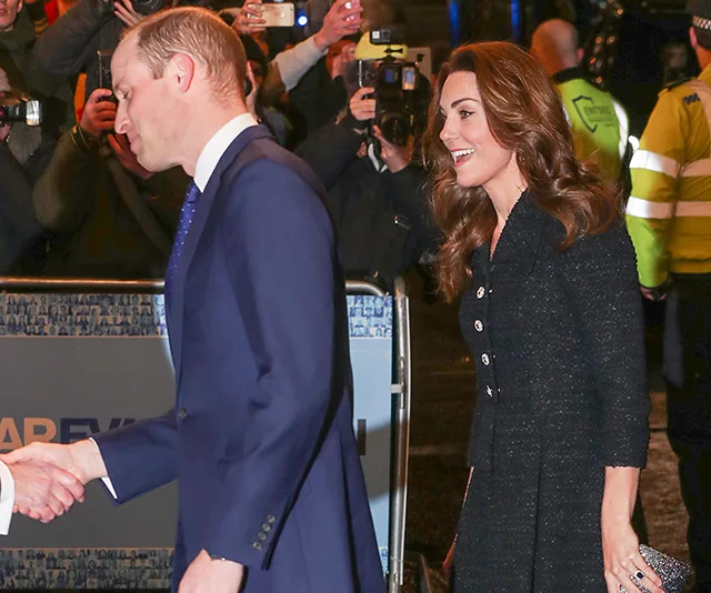 Prince William and Kate Middleton greet attendees at a theater event, surrounded by photographers.