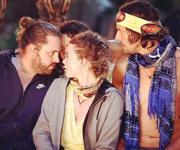 Three contestants on Survivor, two men and a woman, intensely discussing at a tribal council setting.