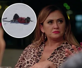A woman in a leopard print top looks concerned at a dinner table. Inset shows a person lying on snow in ski gear.