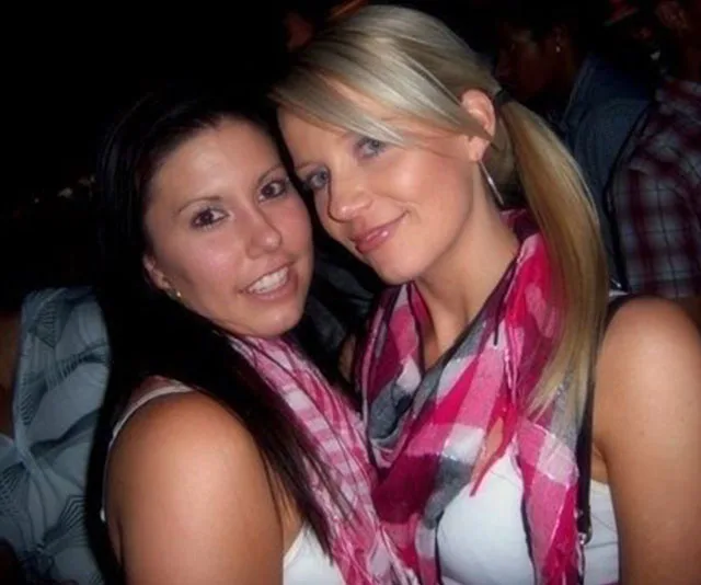 Two women smiling, wearing pink checkered scarves at a social event.