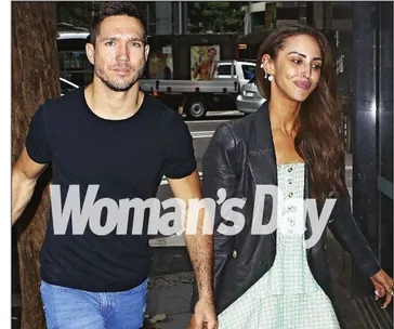 Couple holding hands on the street, woman in a green dress and jacket, man in a black shirt and jeans, "Woman's Day" text overlay.