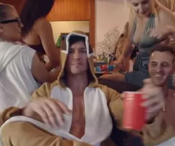 Person in animal costume at a lively indoor party, holding a red cup, surrounded by people socializing.