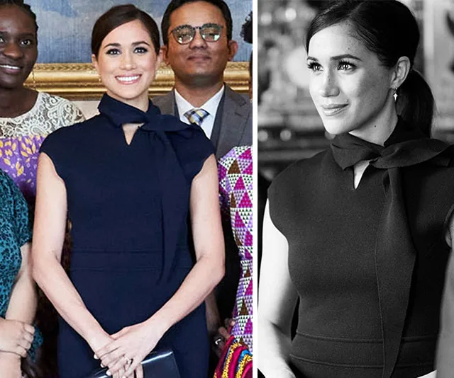 "Meghan Markle in a navy blue Scanlan Theodore dress, smiling, with hair up, among a diverse group of people."