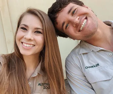 Two people smiling in khaki uniforms, one with "Australia Zoo," the other labeled "Chandler."