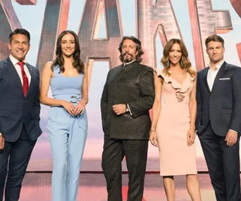 Five people dressed formally stand together in front of a large stage backdrop.