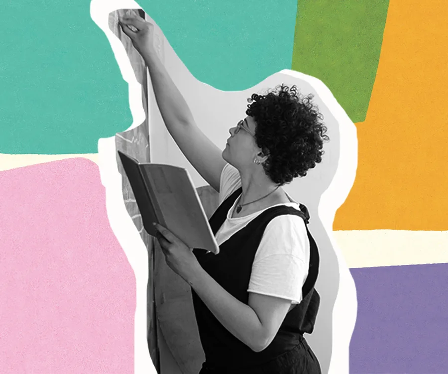 A teacher with curly hair and glasses writing on a board, holding a book; colorful pattern background.