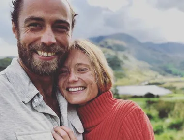 Couple smiling together outdoors in a scenic landscape with mountains in the background.