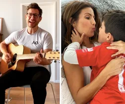 Man in glasses playing guitar next to woman embracing and kissing a young boy wearing a red sports shirt.